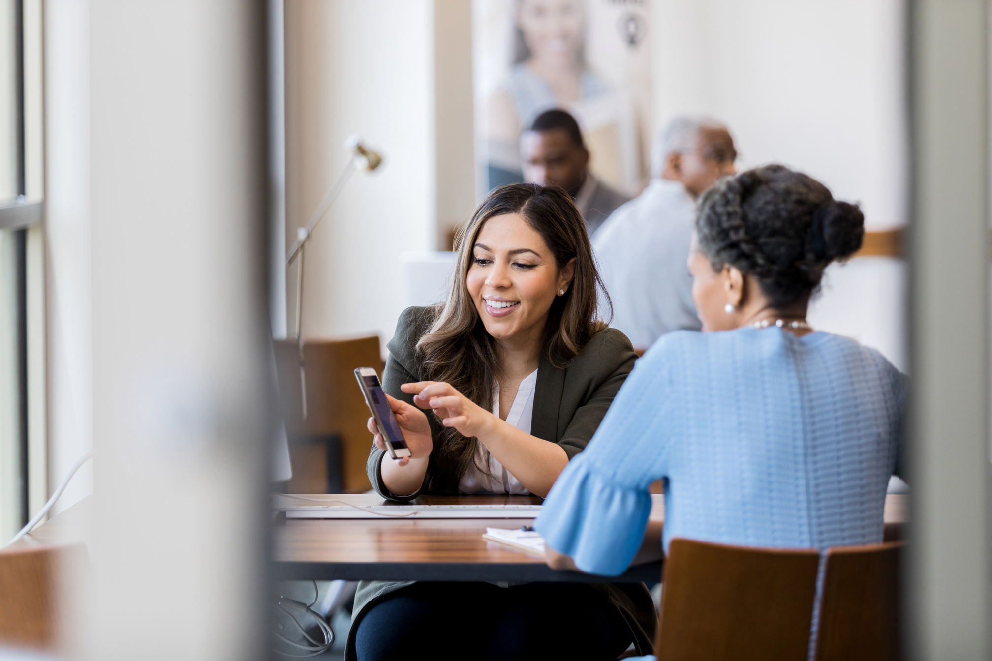 Cheerful bank employee shows customer banking app